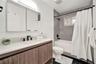 Bathroom featuring a wood-finish vanity with a white countertop, large mirrored medicine cabinet, matte black plumbing fixtures, and a tub-shower comb