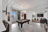 Open-concept industrial-style interior featuring high ceilings with exposed ductwork, wood-finish flooring, a multi-globe chandelier, and sliding glas