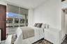 Floor-to-ceiling sliding glass door, private balcony, wood-finish flooring, and integrated full-height storage cabinetry