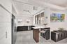 Modern kitchen featuring matte charcoal cabinetry, a built-in peninsula with a wood-finish base, stone-surface countertops, wood-finish flooring, and 