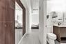 Wood-finish floor-to-ceiling cabinetry with mirrored panels, exposed overhead ductwork, wood-finish vanity cabinet with integrated sink, matte black f