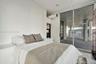 Floor-to-ceiling sliding glass door, private covered balcony with concrete pillars, exposed ceiling ductwork, and white wood-finish flooring