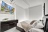 High-ceiling room featuring white walls, light-toned flooring, and wall-to-wall automated roller shades