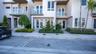 Contemporary multi-story exterior featuring smooth stucco facade, glass-paneled balconies, French-style entry doors, and professional landscaping