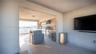 Covered outdoor kitchen featuring a stainless steel grill, range hood, under-counter refrigeration, and stone-finish countertops, complemented by tile