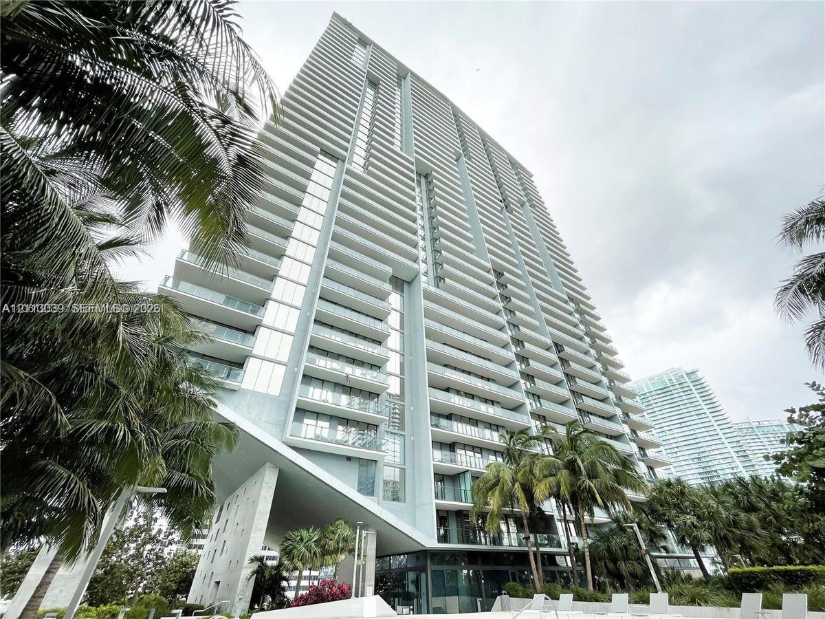 High-rise structure featuring floor-to-ceiling glass paneling, cantilevered architectural design, and private balconies with glass railings