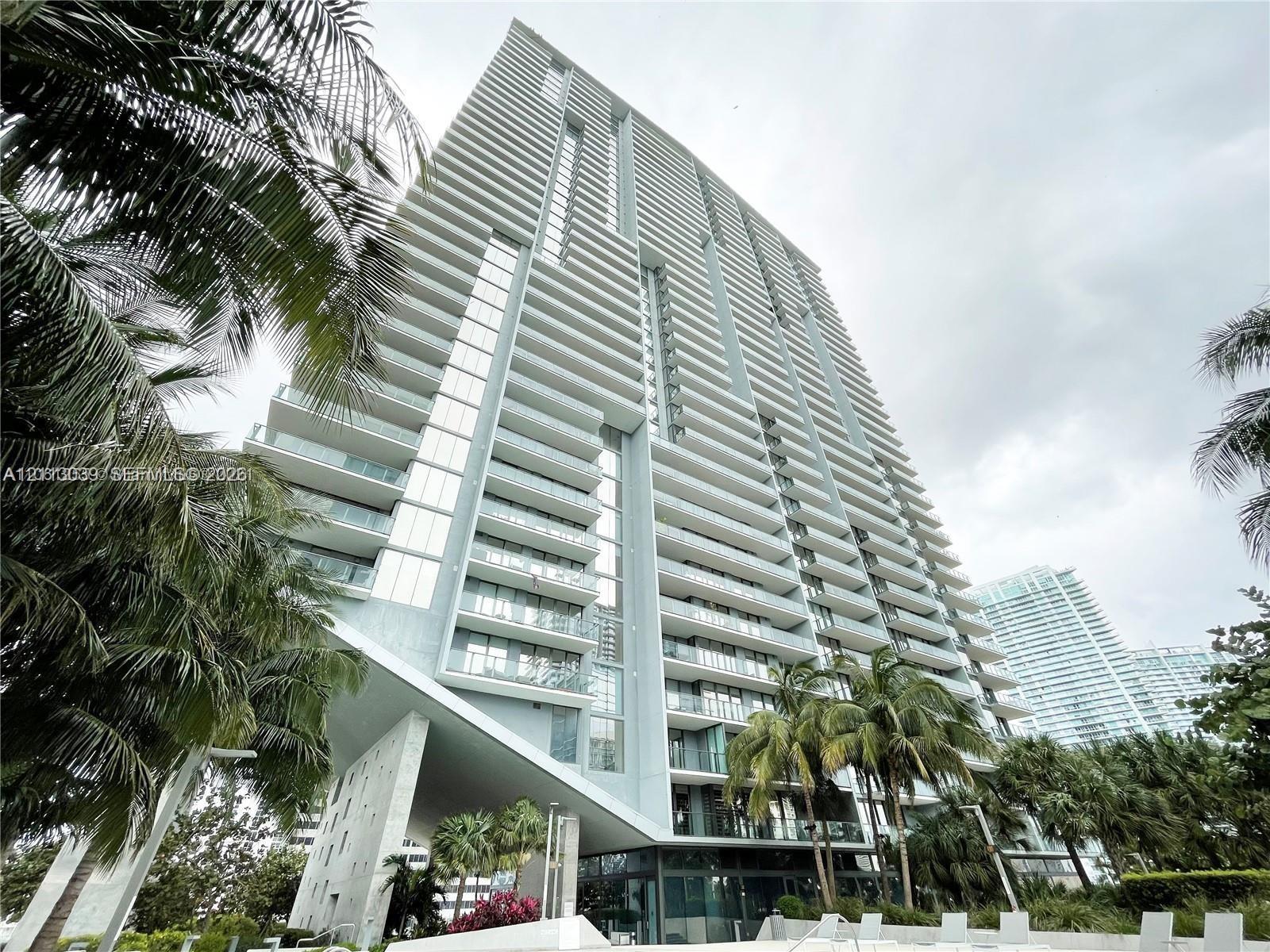 High-rise structure featuring floor-to-ceiling glass paneling, cantilevered architectural design, and private balconies with glass railings