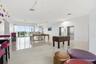 Open-concept common area featuring high-gloss tile flooring, floor-to-ceiling glass wall, recessed track lighting, and dual elevator access