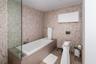 Full-height mosaic tile wall surfacing, deep rectangular soaking tub with deck-mounted chrome faucet, glass panel enclosure, and wall-mounted water cl