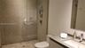 Walk-in shower featuring a glass enclosure and tiled surround, flat-panel vanity with a solid-surface countertop, rectangular undermount sink, and wal