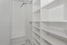 Built-in storage closet featuring white shelving units and integrated metal clothing rods