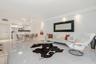 Open-concept living space featuring high-gloss tile flooring, recessed ceiling lighting, and a breakfast bar with stone-finish countertops