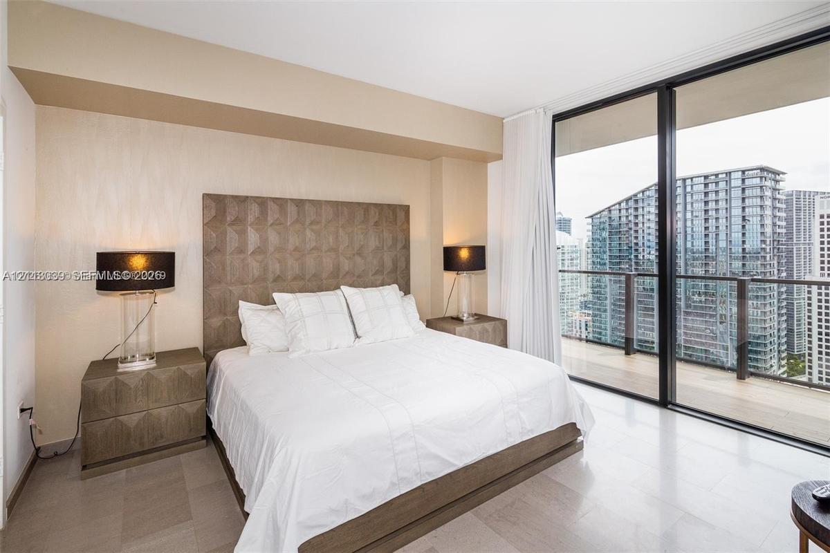 Floor-to-ceiling glass walls, expansive private balcony, stone-finish flooring, and recessed ceiling soffit