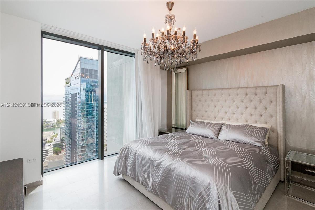 Floor-to-ceiling windows, crystal chandelier, polished stone flooring, and textured wall accent
