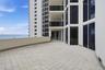 Expansive tiled terrace featuring a solid-surface perimeter wall, floor-to-ceiling glass windows, and sliding glass doors