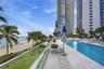Oceanfront swimming pool with tiled surround, glass panel railing, and direct sandy beach access