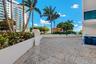 Outdoor terrace featuring patterned paver flooring, perimeter concrete planter walls, and palm tree landscaping