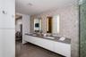 Floating dual-sink vanity with a solid surface countertop, mosaic tile backsplash, integrated rectangular sinks, and wall-mounted mirrors with built-i