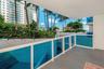 Covered balcony with white railings and blue-tinted glass panels, featuring exterior landscaping with palm trees