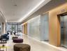 Modern lobby featuring large-format stone flooring, wood-panel wall accents, recessed cove lighting, and floor-to-ceiling frosted glass paneling