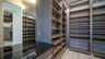 Custom walk-in closet featuring extensive built-in shelving, integrated strip lighting, full-length mirror panels, a dark-toned countertop,