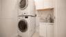 Laundry space featuring a stacked washer and dryer, stainless steel utility sink