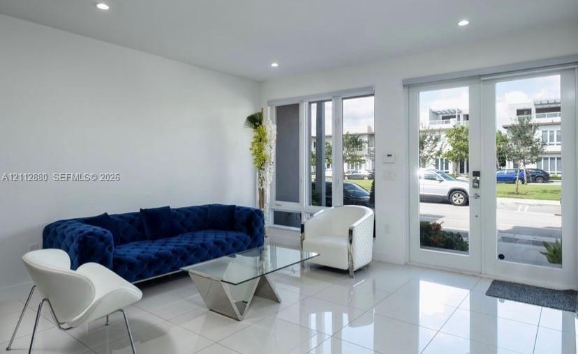 Interior space featuring large-format tile flooring, recessed lighting, expansive multi-pane windows, and glass-paneled double entry doors