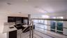 Kitchen featuring dark cabinetry, quartz countertops, a stainless steel range hood, built-in double wall ovens, and large-format tile flooring