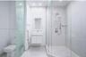 Bathroom featuring a glass-enclosed shower with a rainfall showerhead and handheld sprayer, a floating vanity with a rectangular sink, a recessed wall