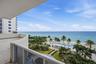 Covered balcony featuring tile flooring and a glass-paneled railing connects to oversized large terrace.