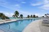 Swimming pool with tiered entry steps, stone paver decking, and a glass panel perimeter railing