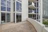 Expansive private balcony featuring patterned paver flooring, floor-to-ceiling glass paneling, and glass-paneled railings