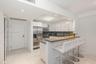Kitchen featuring white flat-panel cabinetry, stainless steel appliances, a stone countertop peninsula, and polished tile flooring