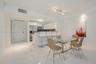 Open-concept kitchen featuring high-gloss cabinetry, stainless steel appliances, a breakfast bar, and polished white tile flooring
