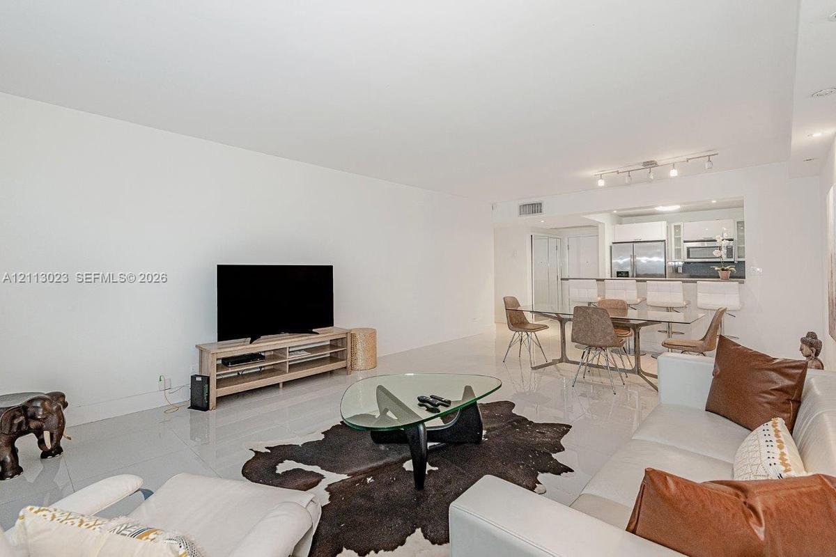 Open floor plan featuring polished tile flooring, recessed lighting, and a kitchen breakfast bar