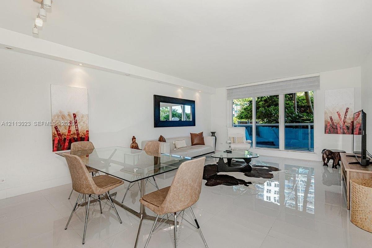 Open-concept living space featuring high-gloss tile flooring, floor-to-ceiling glass paneling, recessed lighting, and integrated track lighting