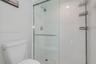 Glass-enclosed shower with white wall tile, mosaic tile shower floor, and chrome fixtures