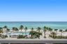 Direct waterfront access with expansive ocean horizon, resort-style swimming pool, integrated poolside bar, and mature palm landscaping