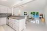 Kitchen featuring glossy white flat-panel cabinetry, solid-surface countertops, stainless steel undermount sink, and recessed lighting, complemented b