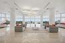 Expansive open-concept space featuring polished stone flooring, floor-to-ceiling windows, sculptural circular pendant lighting, recessed tray ceiling 