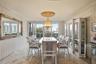 Dining area featuring polished stone flooring, custom built-in cabinetry, crown molding, a decorative ceiling medallion, and a chandelier