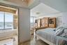 Polished stone flooring, crown molding, built-in recessed lighting, decorative crystal-style chandelier, and jetted corner soaking tub featuring stone