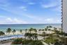 Elevated perspective featuring direct oceanfront access, a sprawling swimming pool with surrounding terrace, landscaped grounds with mature palms, and