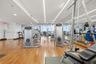 Fitness facility featuring wood-finish flooring, floor-to-ceiling mirrored walls, and recessed linear lighting