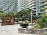 Outdoor terrace featuring large-format concrete pavers, custom dark wood-slatted privacy screens, a natural stone retaining wall, and integrated metal
