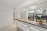 Kitchen featuring a stone-surface breakfast bar, white cabinetry, stainless steel appliances, and tile flooring, illuminated by recessed lighting
