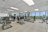 Well-equipped oceanfront fitness center featuring exercise machines, mirrored walls, and expansive windows overlooking the beach.