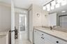 Additional view of the primary bathroom showcasing granite countertops, white cabinetry, and updated lighting.