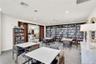 Spacious community library featuring an extensive collection of books, comfortable seating, and tables for cards and games.