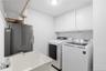 Separate laundry room featuring a full-size washer and dryer, utility sink, and overhead cabinetry for additional storage.